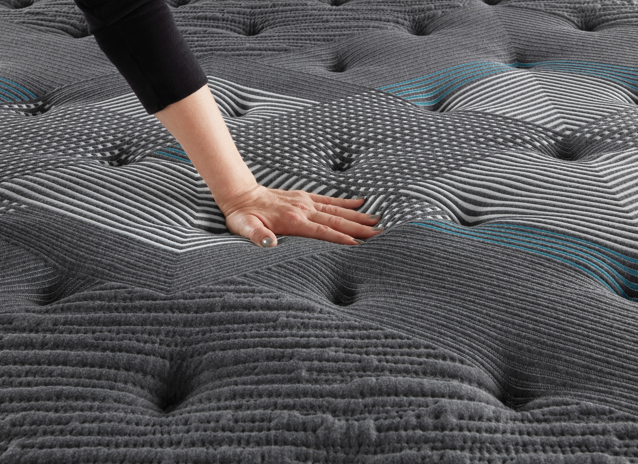 woman presses down on surface of Beautyrest mattress