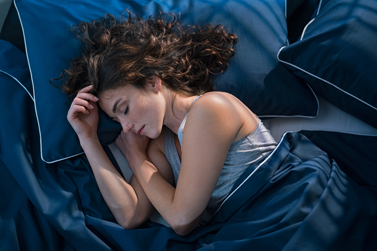 woman sleeping on a bed of navy blue sheets