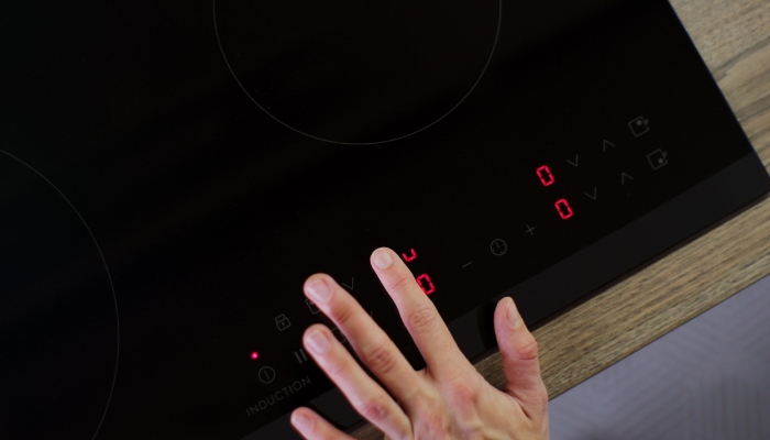 Closeup of hand checking indicator controls on electric cooktop