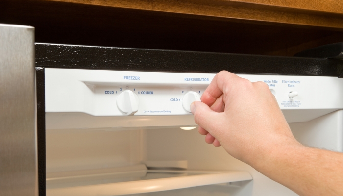 Closeup of hand adjusting the temperature on refrigerator