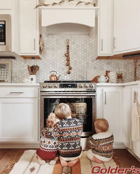Children gather around an oven in a kitchen