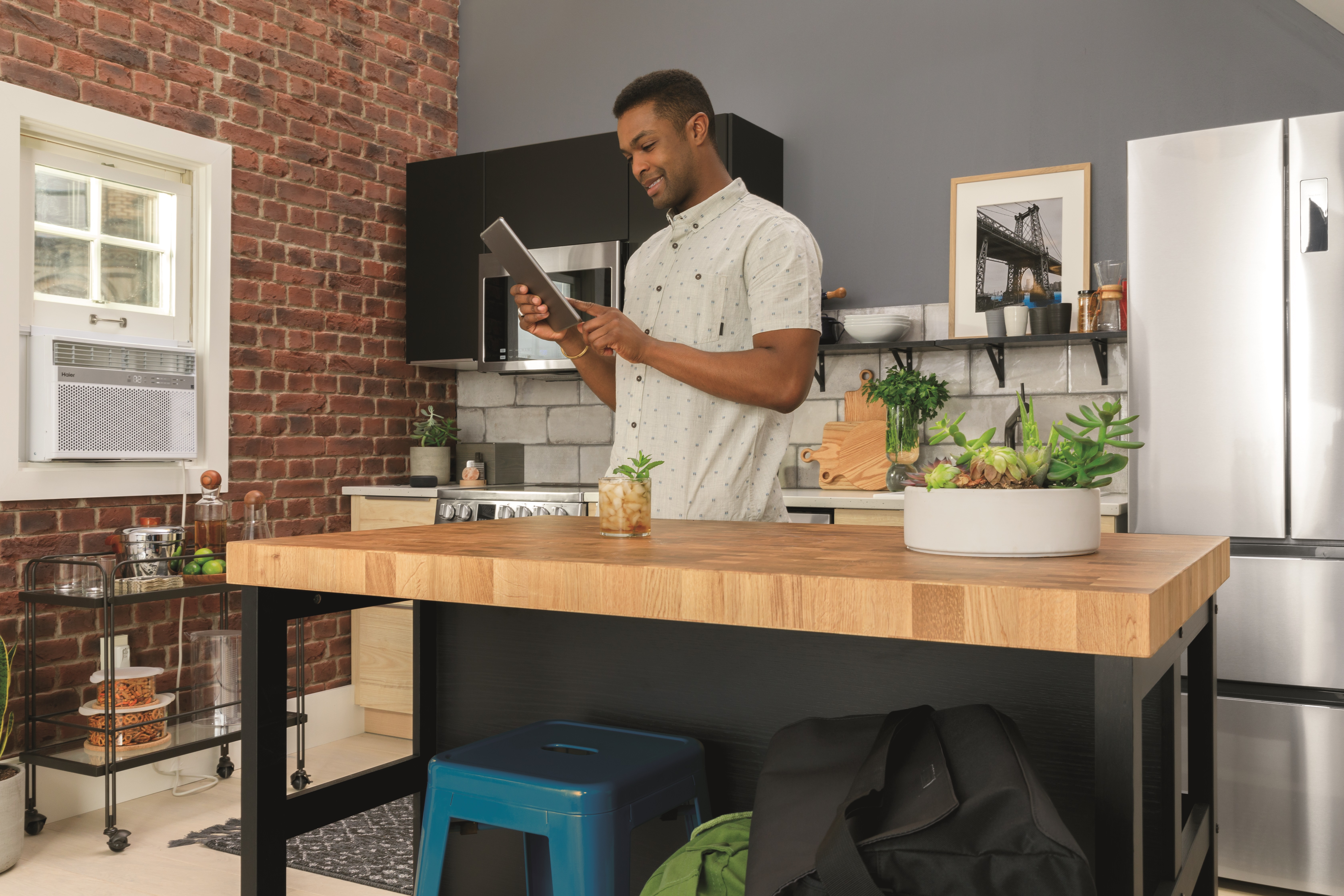 Man holding tablet and smiling in the middle of the kitchen