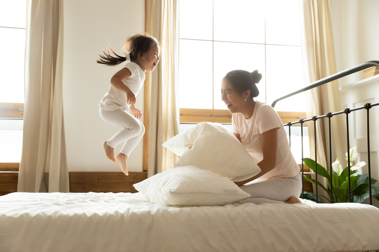 mom and daughter play together on mattress