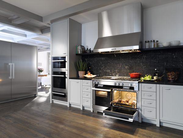 A 48 inch range, wall mounted range hood, and oven are installed in a modern kitchen
