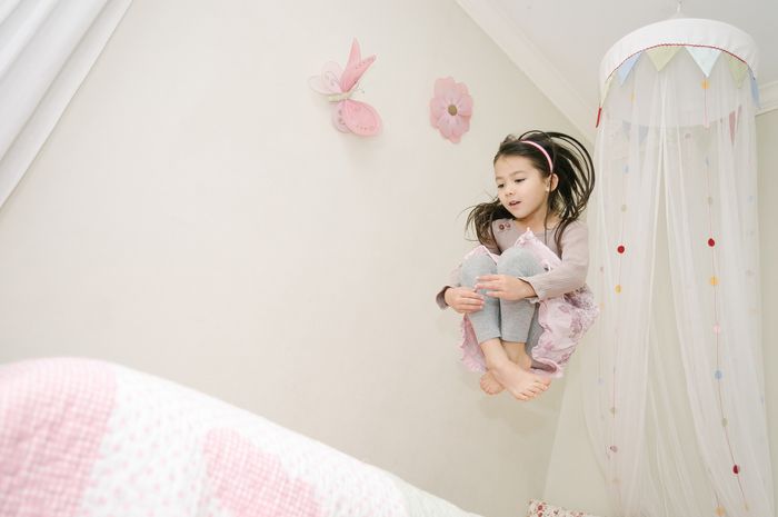 Young girl jumping on her bed