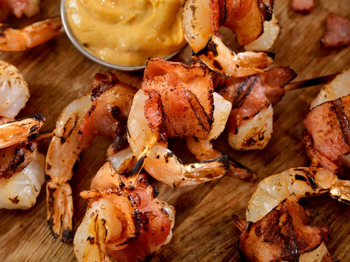 bacon-wrapped shrimp on skewers against the wood