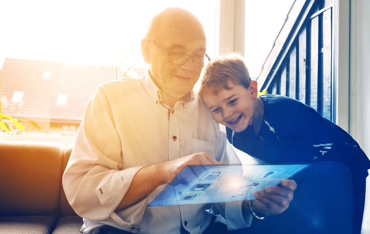 Grandparent using a smart home system with his grandson.