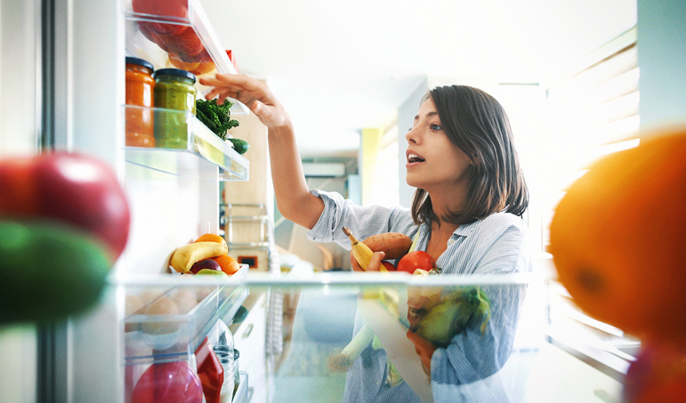 woman grabbing for items in her fridge