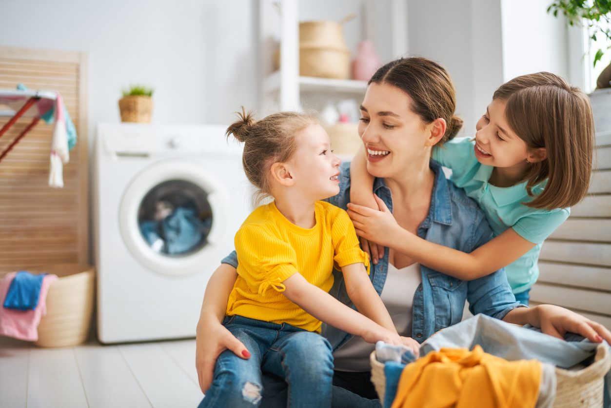 a mother and her two young daughters do laundry
