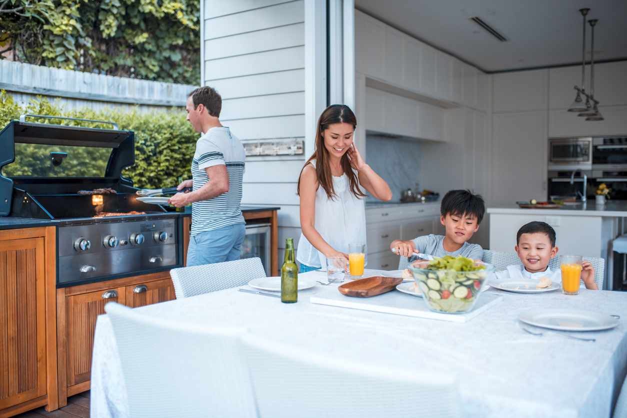 family of four grilling and eating in outdoor seating area