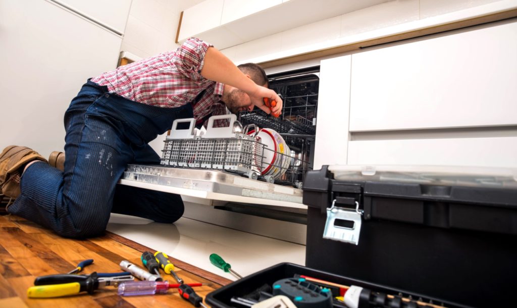 Professional fixing a broken dishwasher