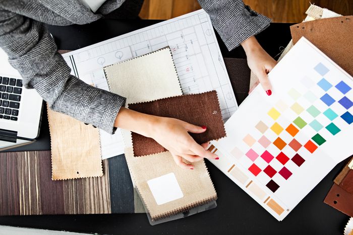 Overhead shot of a woman looking through paint and fabric swatches on a wooden table.