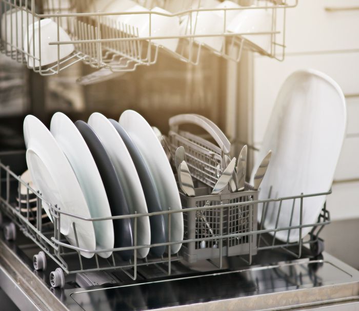 A dishwasher rack full of clean, white dishes.