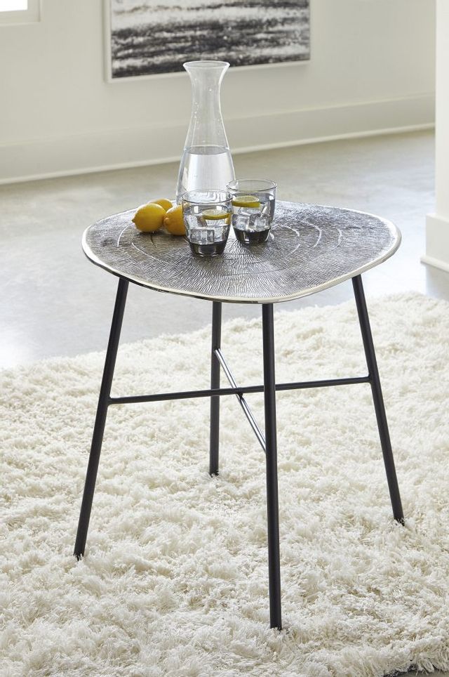 organic-shaped silver-top end table with black legs and a pitcher of water on top
