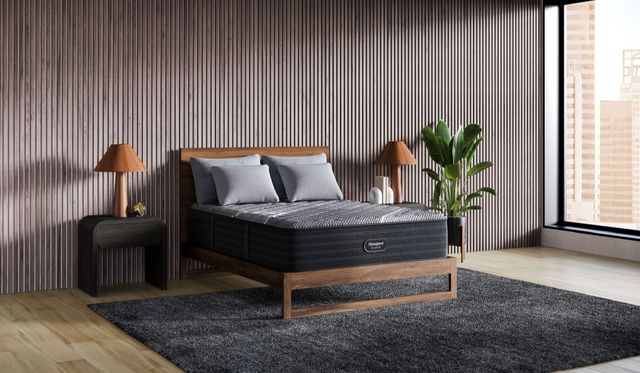 view of a contemporary bedroom with a panel wall, black beautyrest mattress, on a light wood bed frame with two dark wood side tables