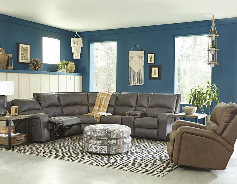 A gray reclining sectional and other furniture in a bright blue room