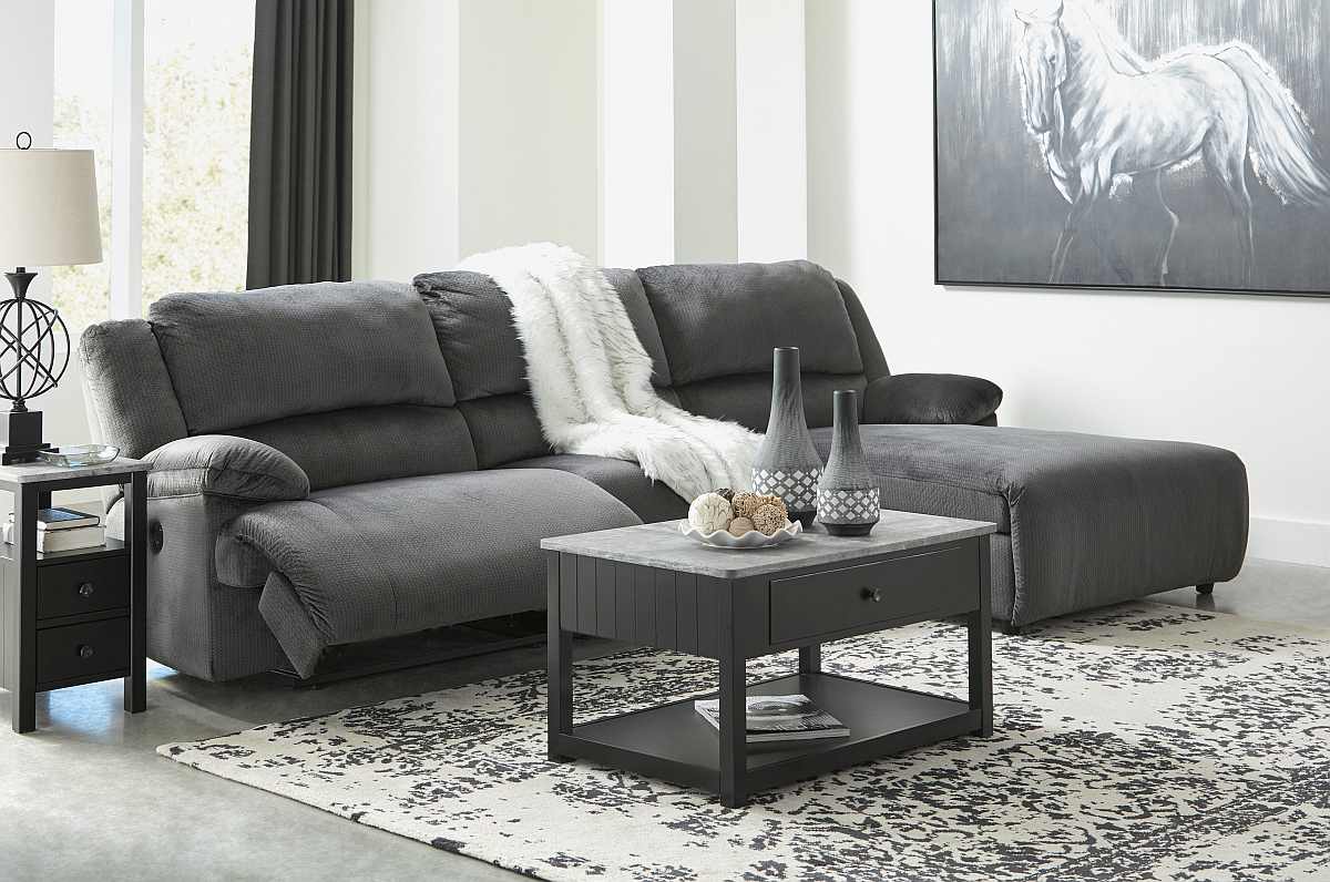 Reclining sectional in charcoal grey with a throw beneath a painting of a white horse