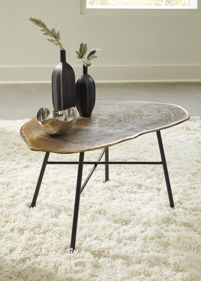 organic-shaped copper-top table on a white faux fur rug decorated with a vase and bowl