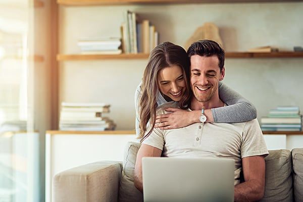 Financing, couple on couch with laptop online shopping
