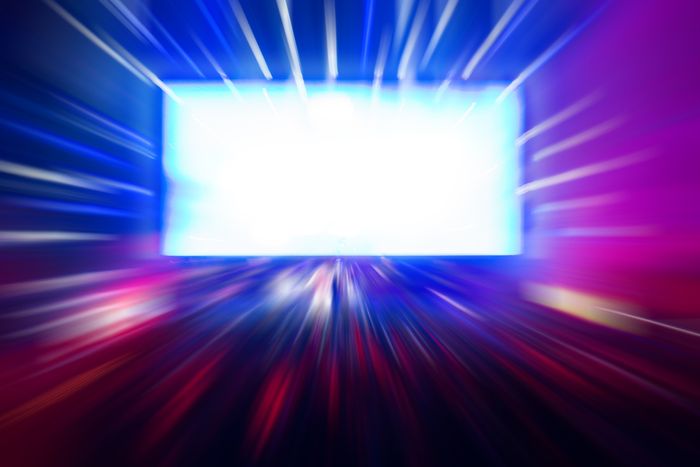 A bright television screen in the center of the shot slightly out of focus with flecks of light moving out from it.