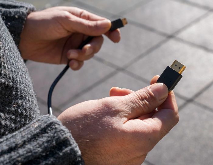 A person holding both ends of an HDMI cord.