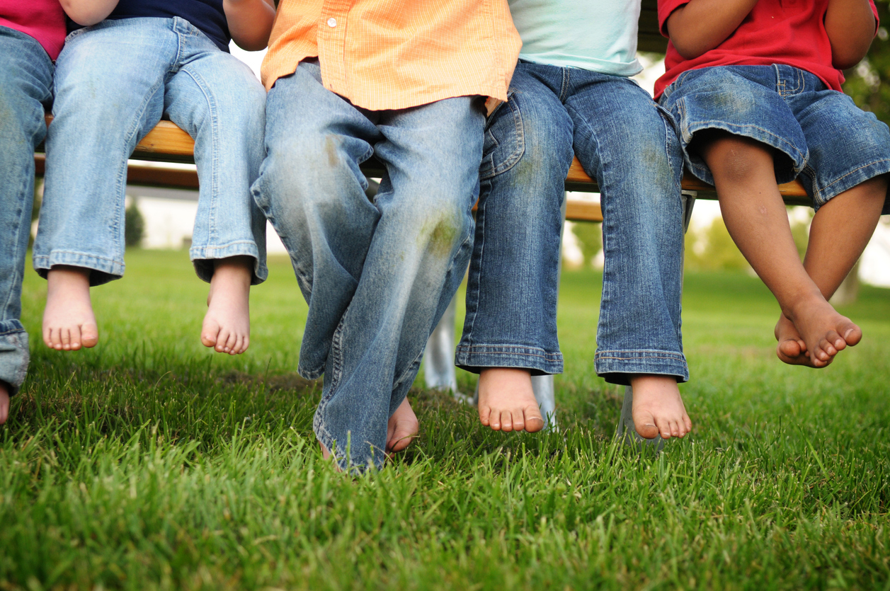 kids sitting on bench with grass stains on their jeans
